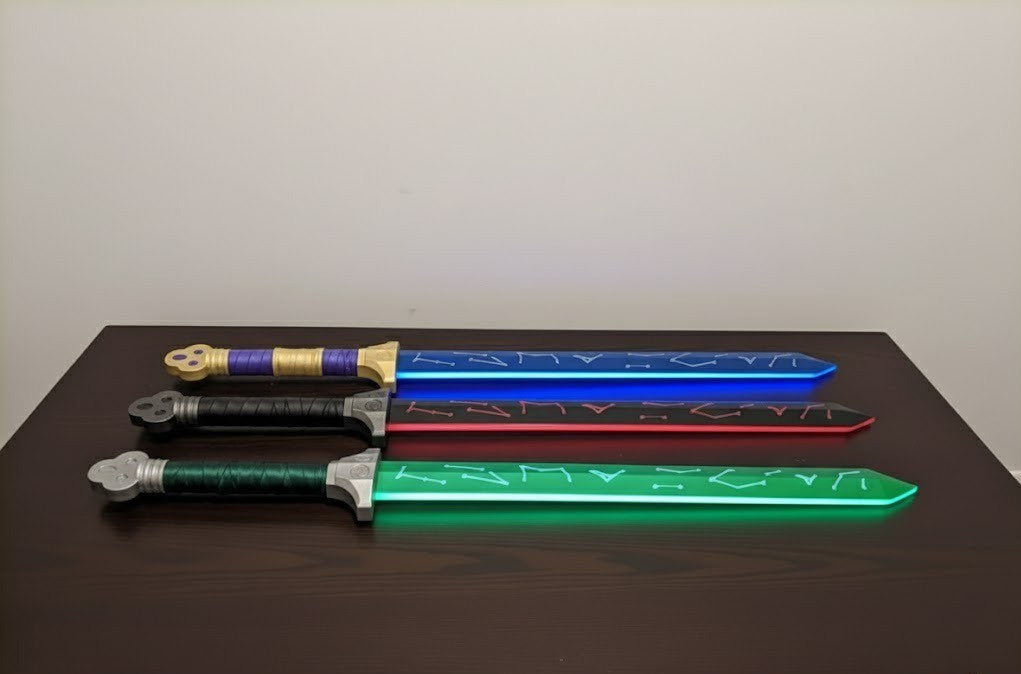 Four toy swords in green, red, blue, and gold on a dark surface with a light gray background